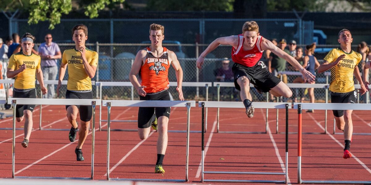 Track athletes jumping hurdles during race