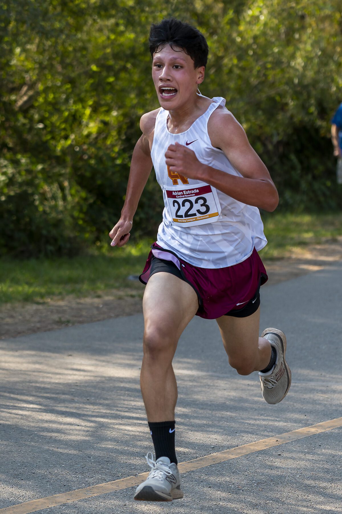 Cross-country runner sprinting on tree-lined path