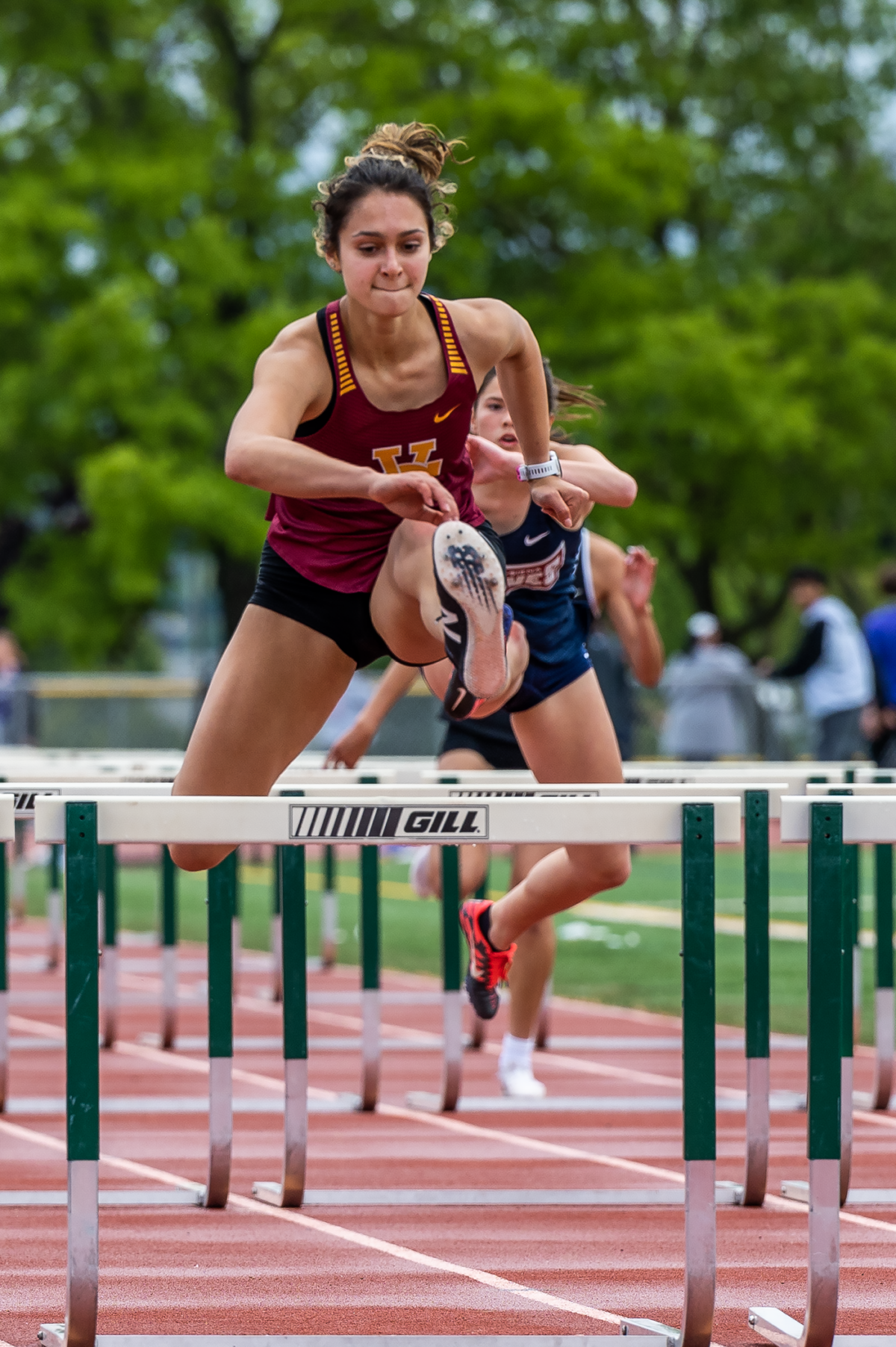 Female athlete leaping over track hurdle