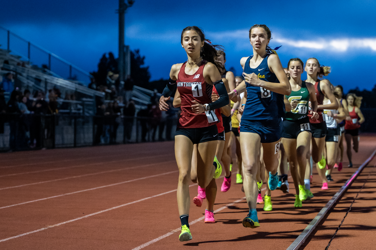 Female runners racing on track at dusk
