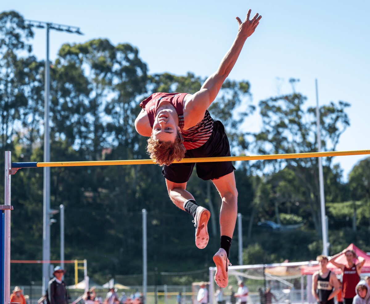 High jumper clearing bar at outdoor track