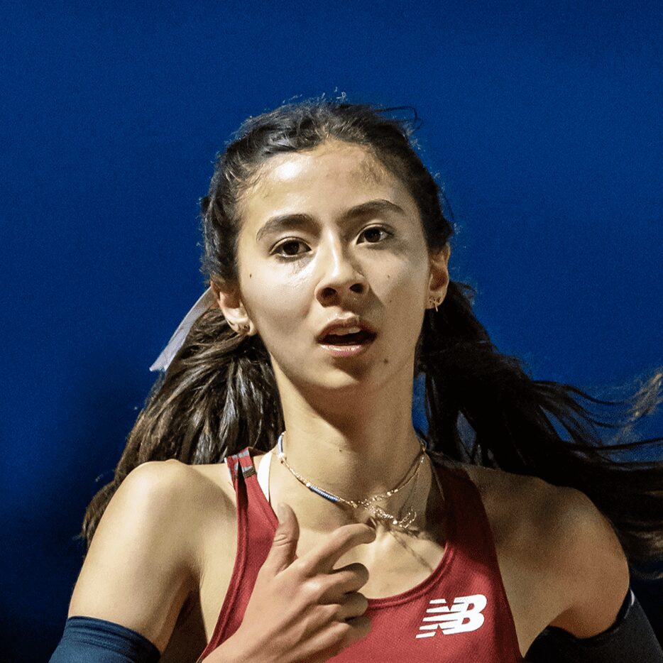 Female track athlete running in maroon jersey