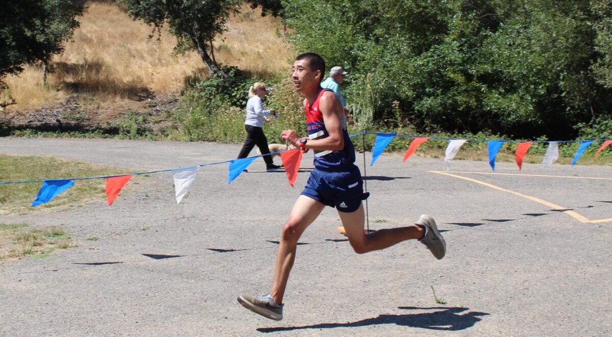 Runner racing past flags on outdoor course