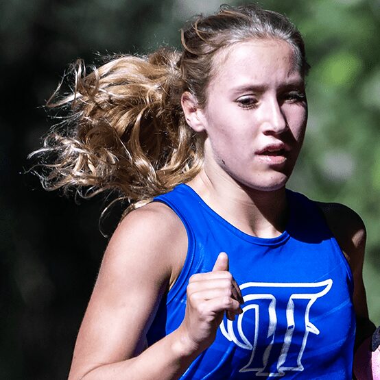 Female runner in blue athletic top mid-stride