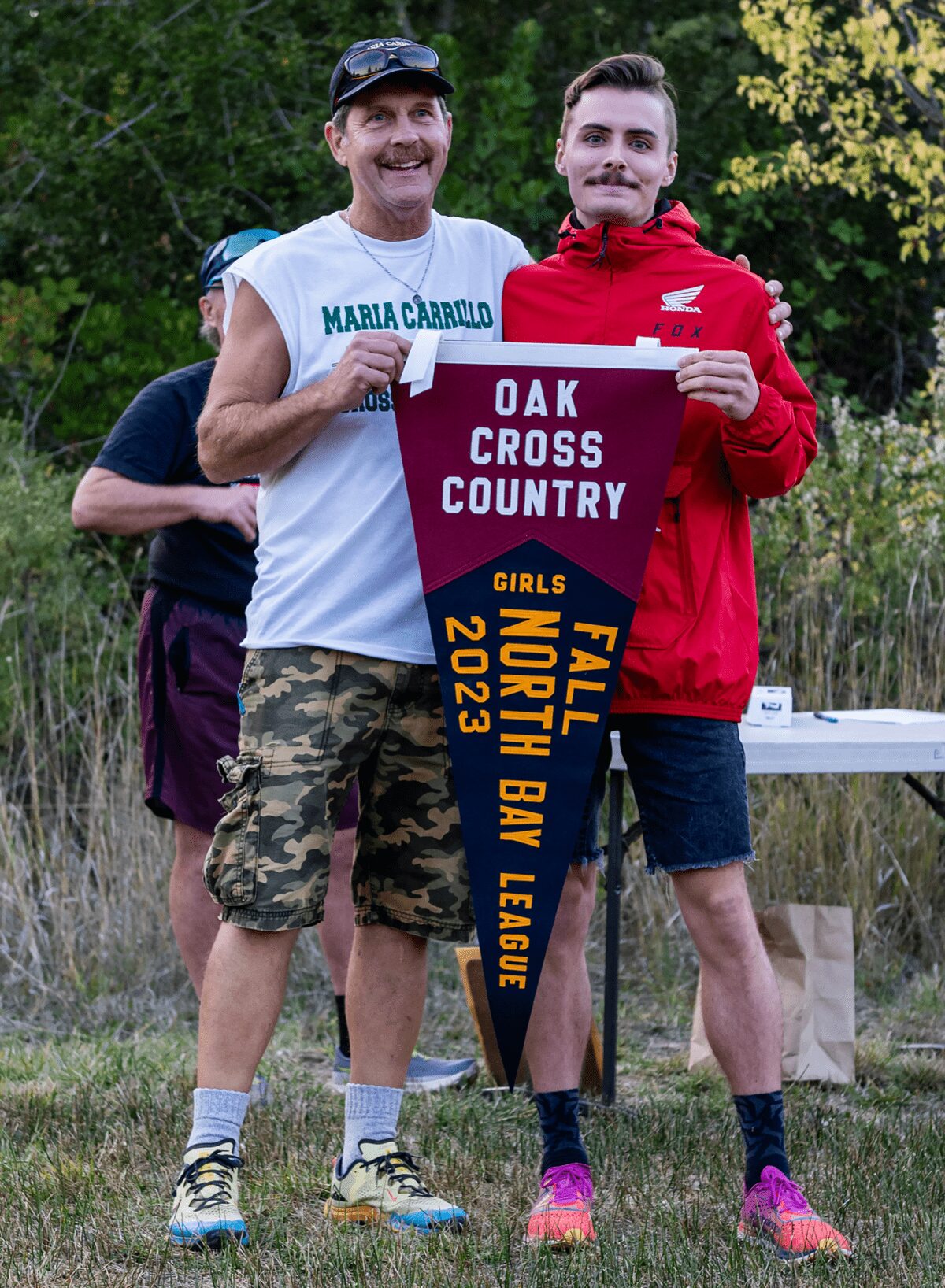 Two people holding Oak Cross Country girls pennant