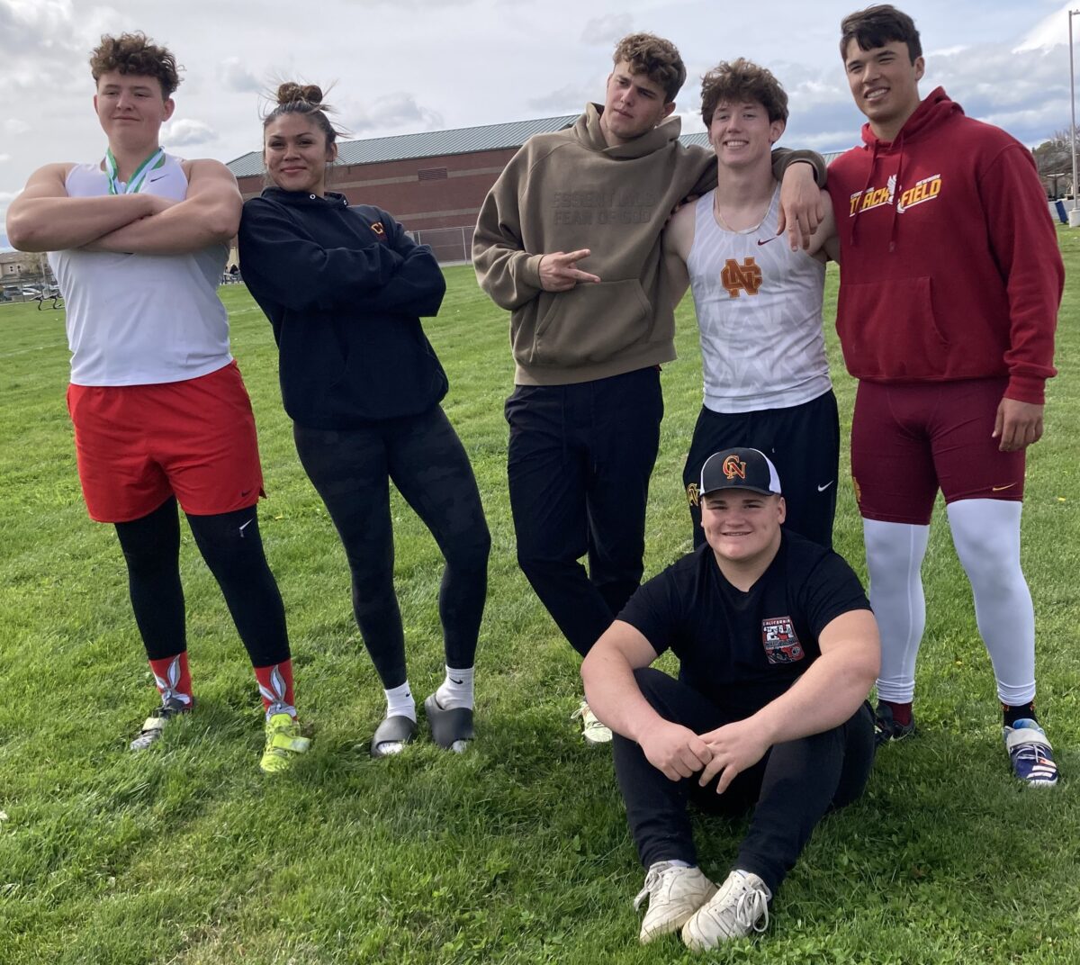 Six high school athletes posing on grassy field