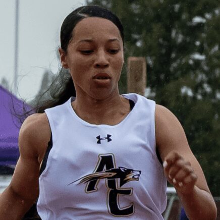 Female athlete sprinting in white AC uniform