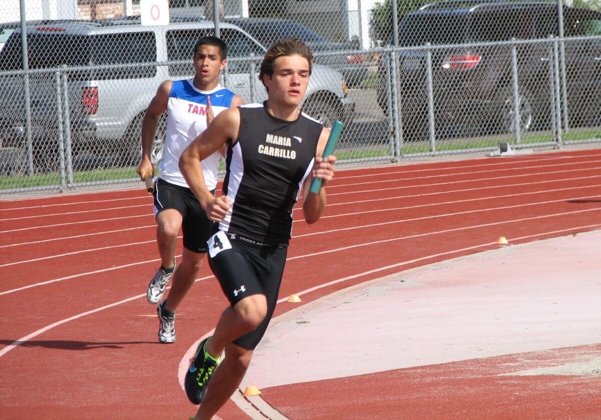 Relay runner passing baton on outdoor track