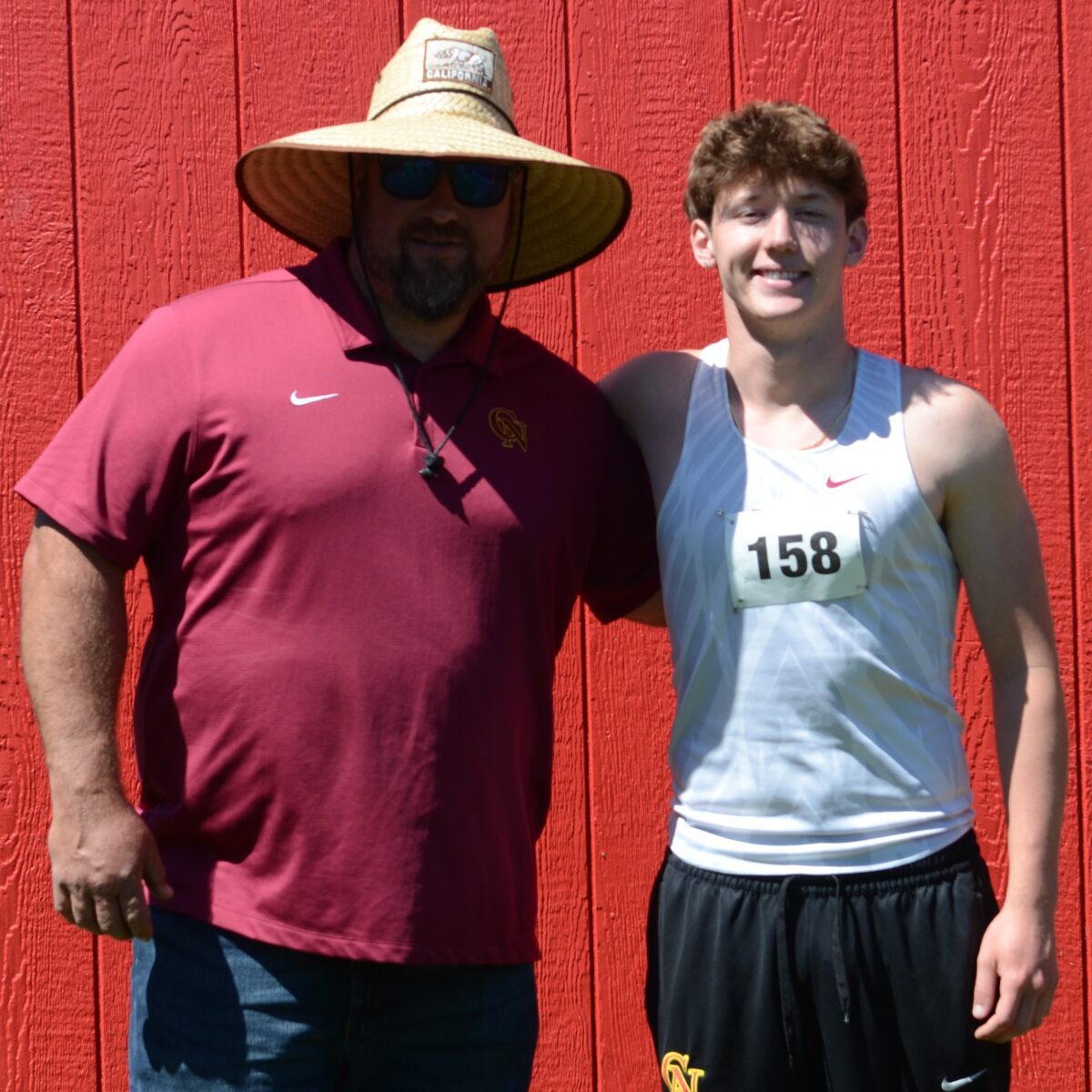 Coach and athlete smiling against red wall