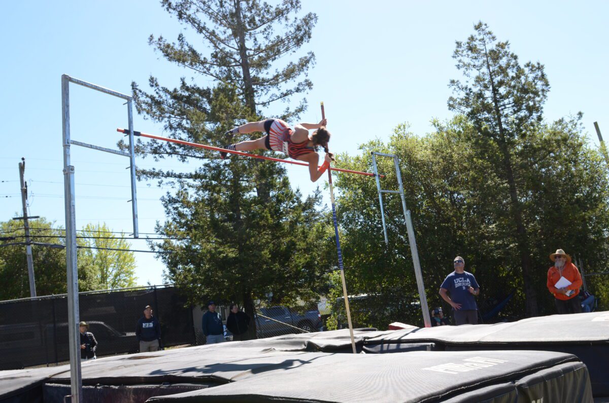 Pole vaulter clearing bar at outdoor track meet