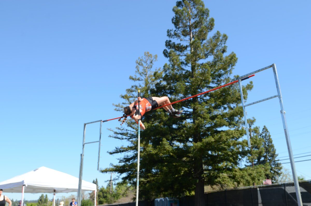 Pole vaulter clearing bar at outdoor meet