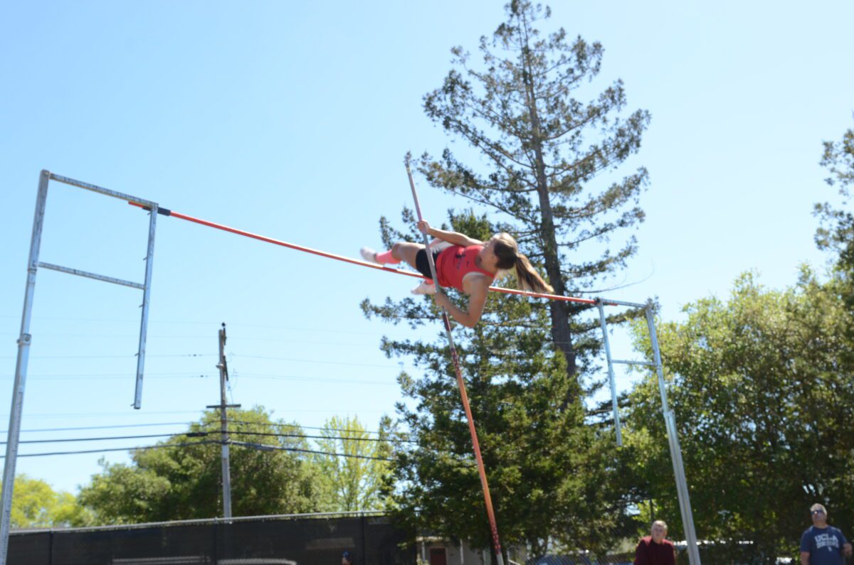 Pole vaulter clearing bar outdoors