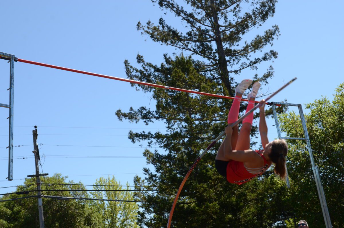 Pole vaulter clearing bar outdoors