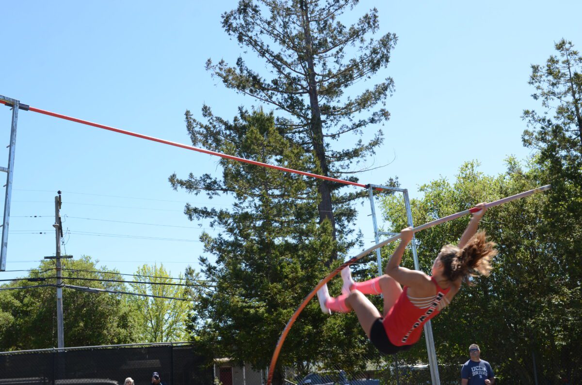 Female pole vaulter clearing bar outdoors
