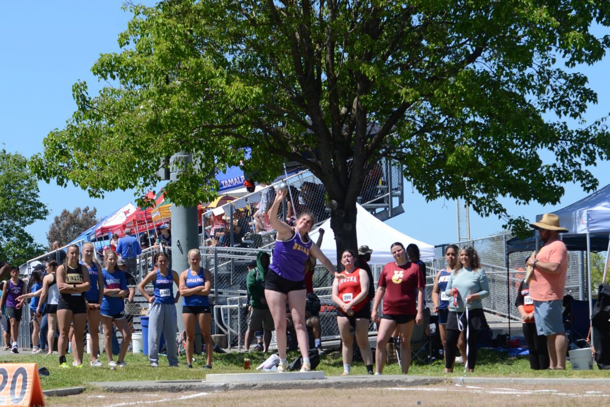 Female athlete throwing shot put at track meet