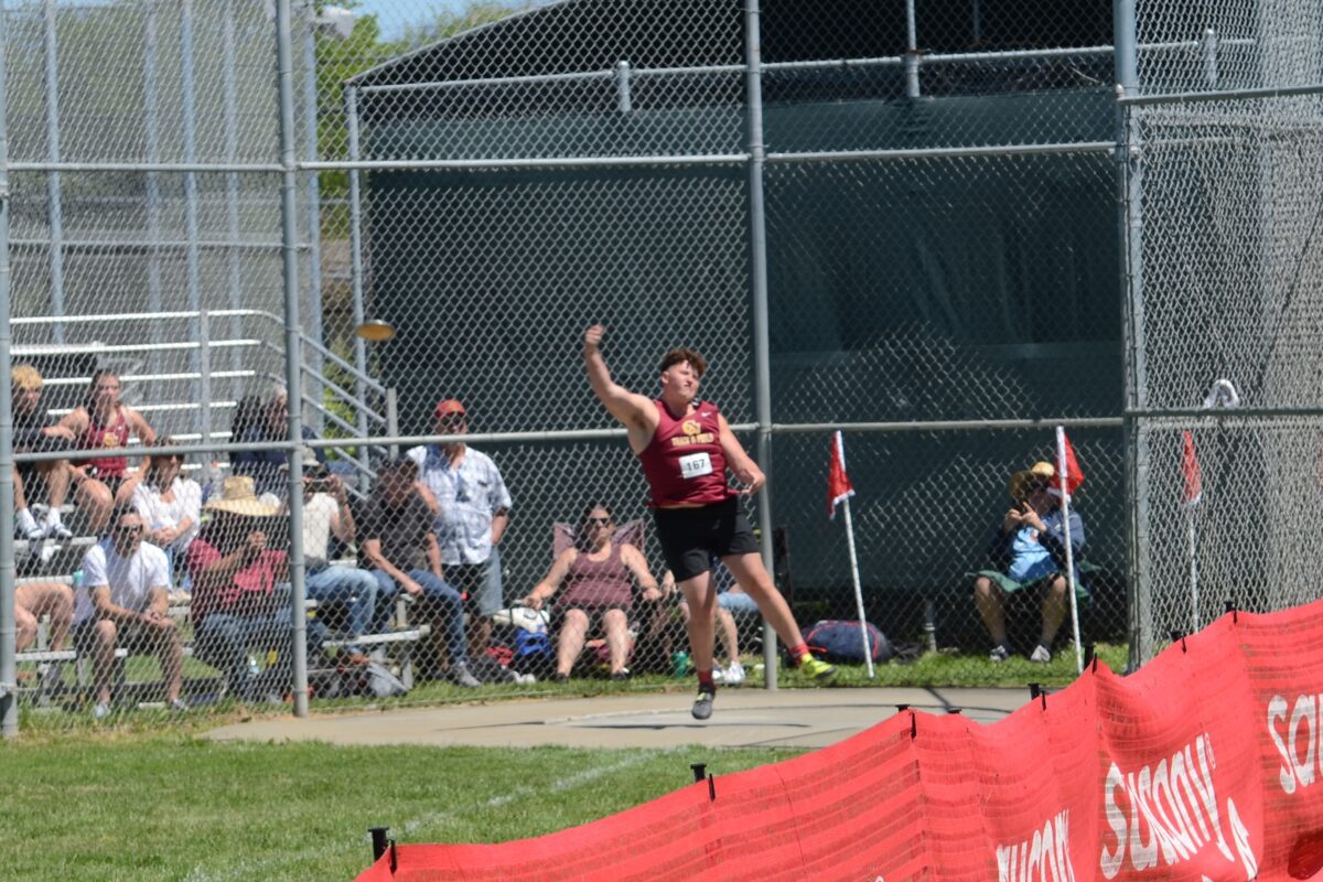 Athlete throwing discus at track meet