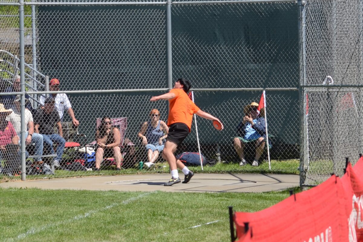 Athlete throwing discus at track meet