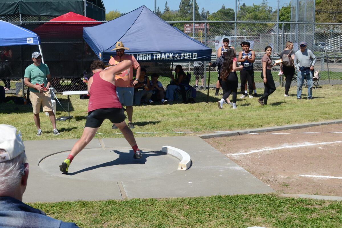 Athlete throwing shot put at track meet