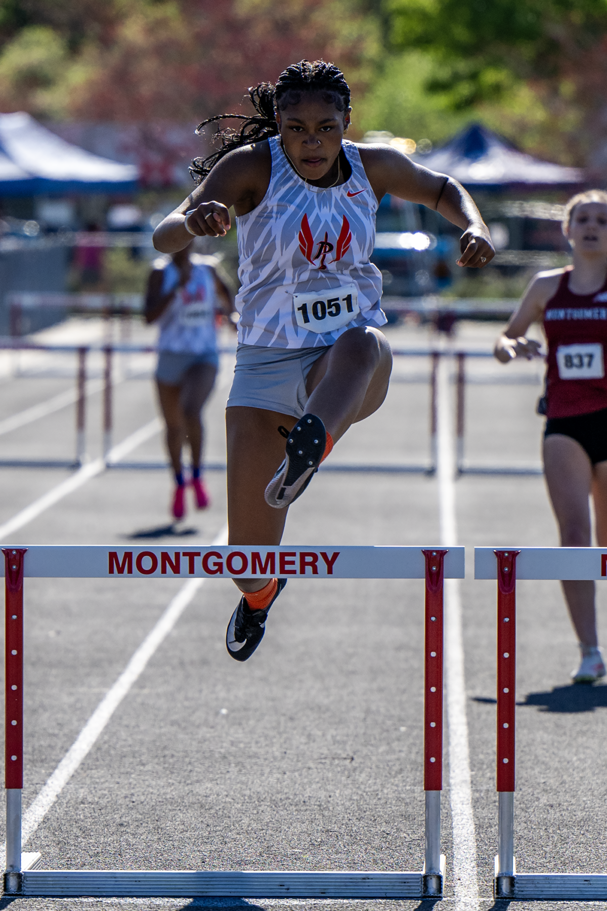 Female athlete leaping over track hurdle