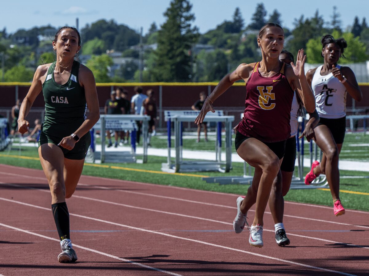 Three female sprinters racing on outdoor track