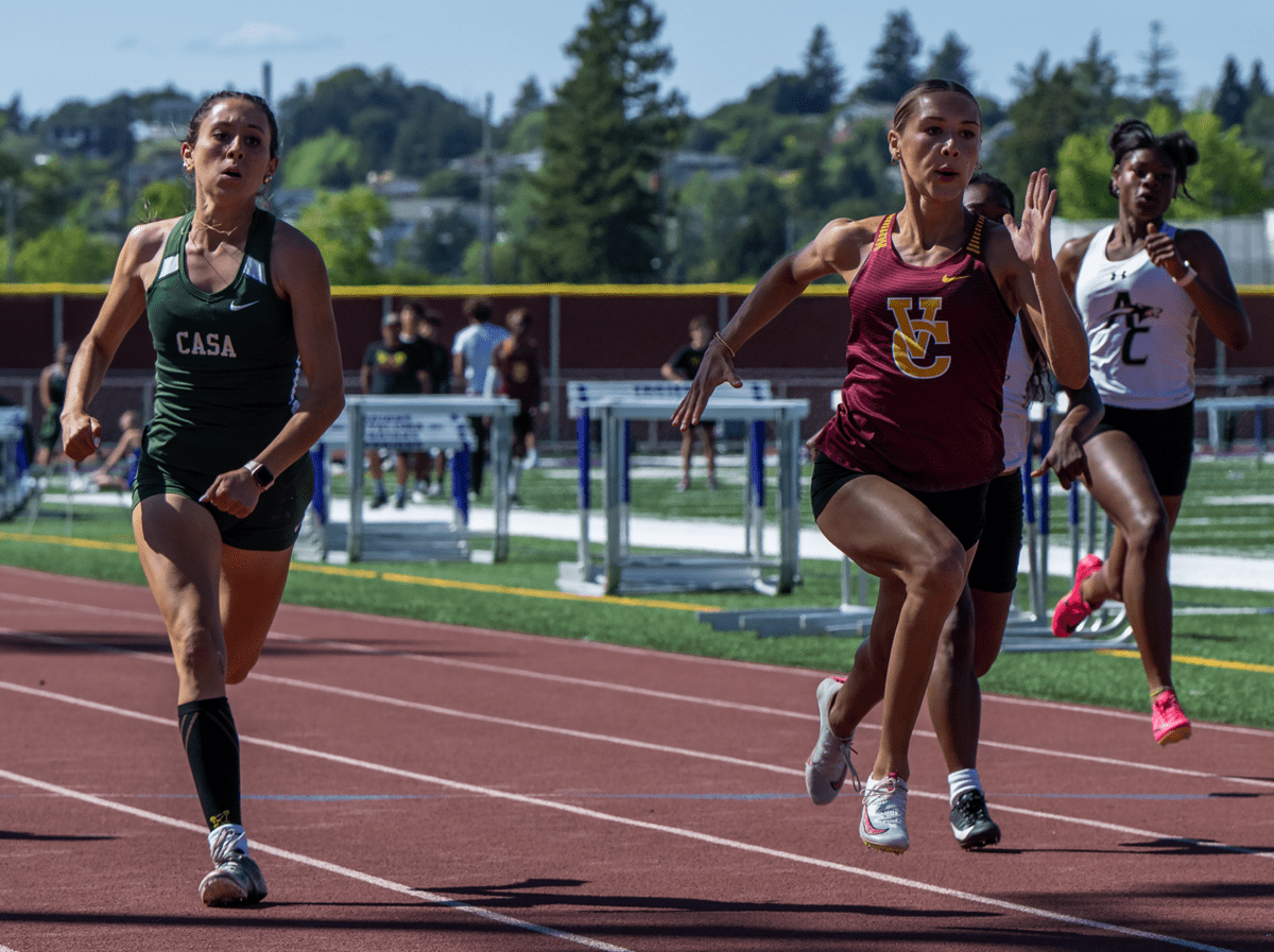 Three female sprinters racing on outdoor track