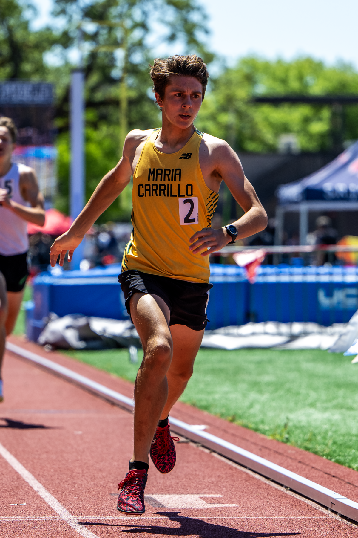 Runner wearing yellow singlet sprinting on track