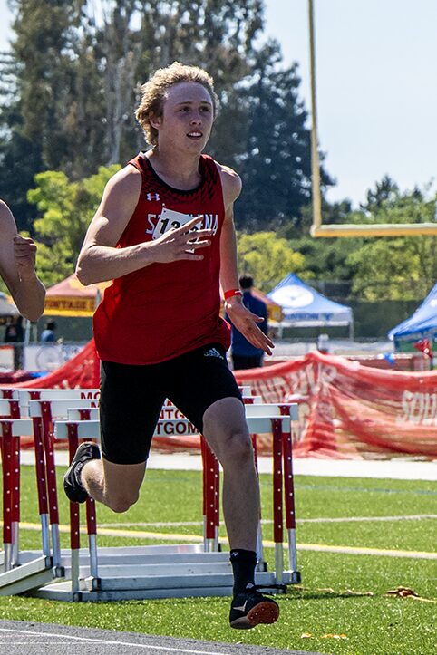 Runner clearing hurdle at outdoor track meet