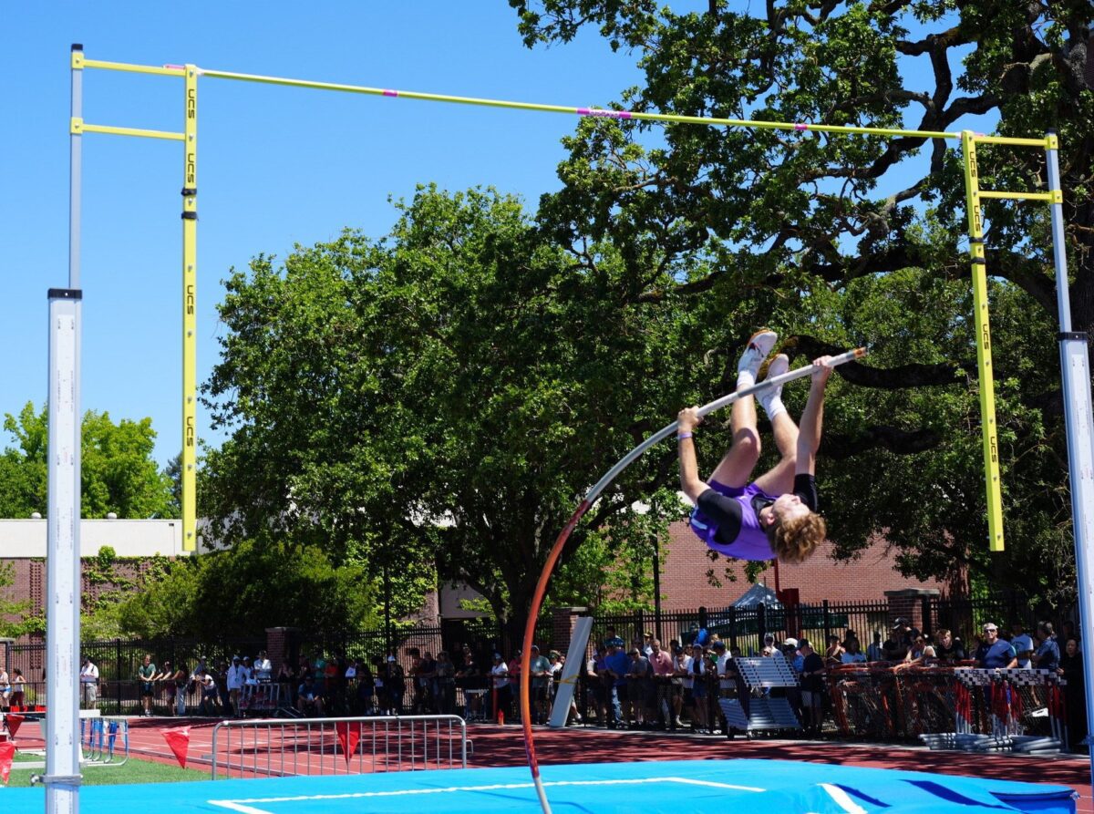 Pole vaulter clearing bar at outdoor track