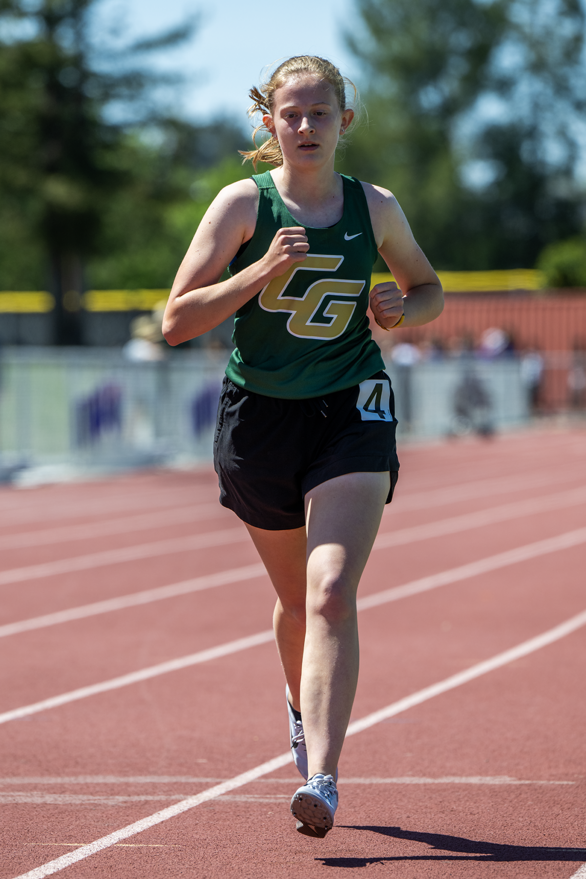 Runner in green singlet racing on track