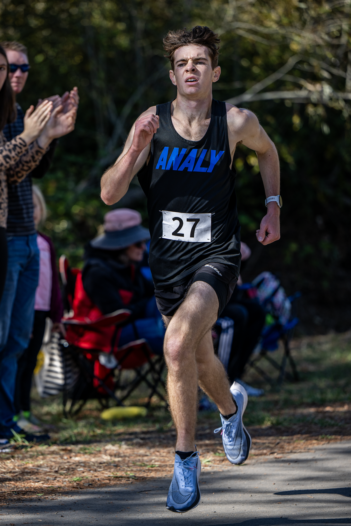 Young runner sprinting outdoors wearing bib 27