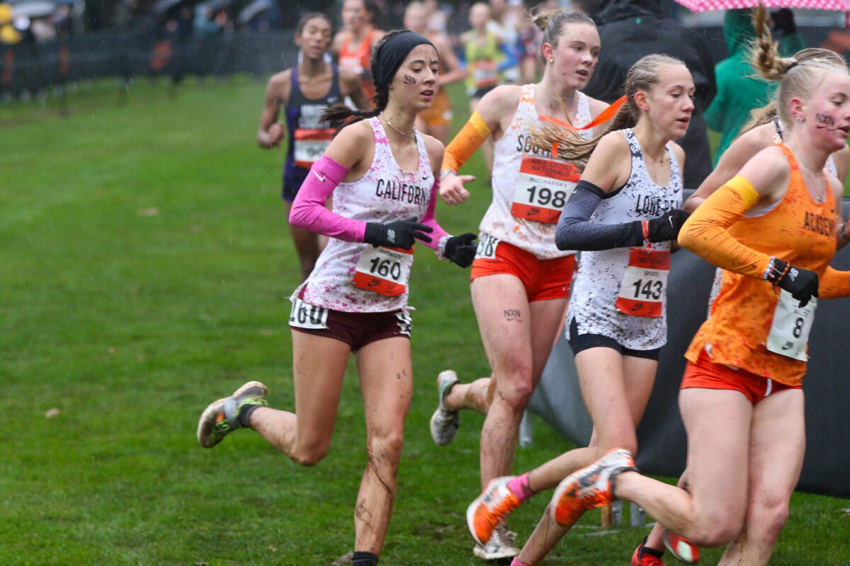 Women cross-country runners racing through muddy grass