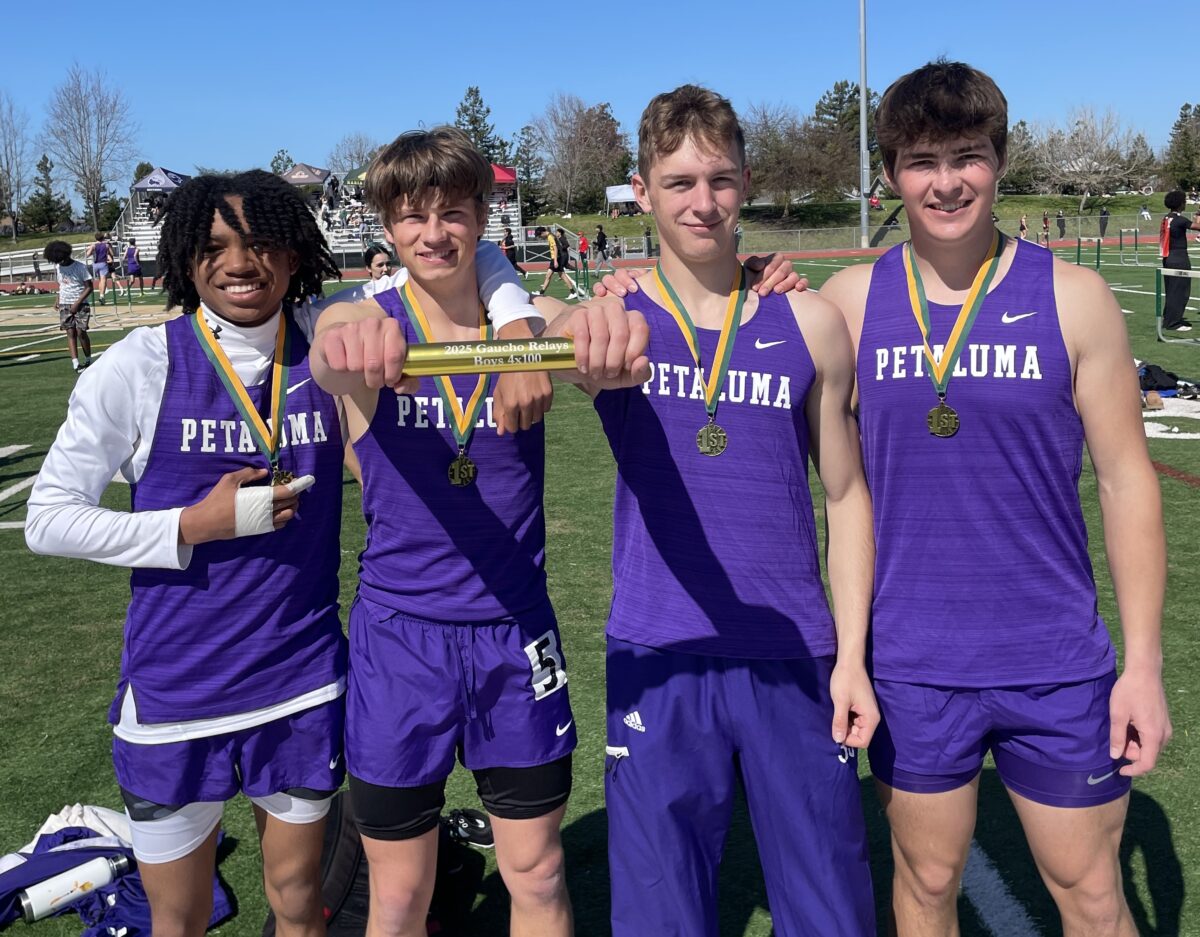 Four athletes in purple jerseys holding baton