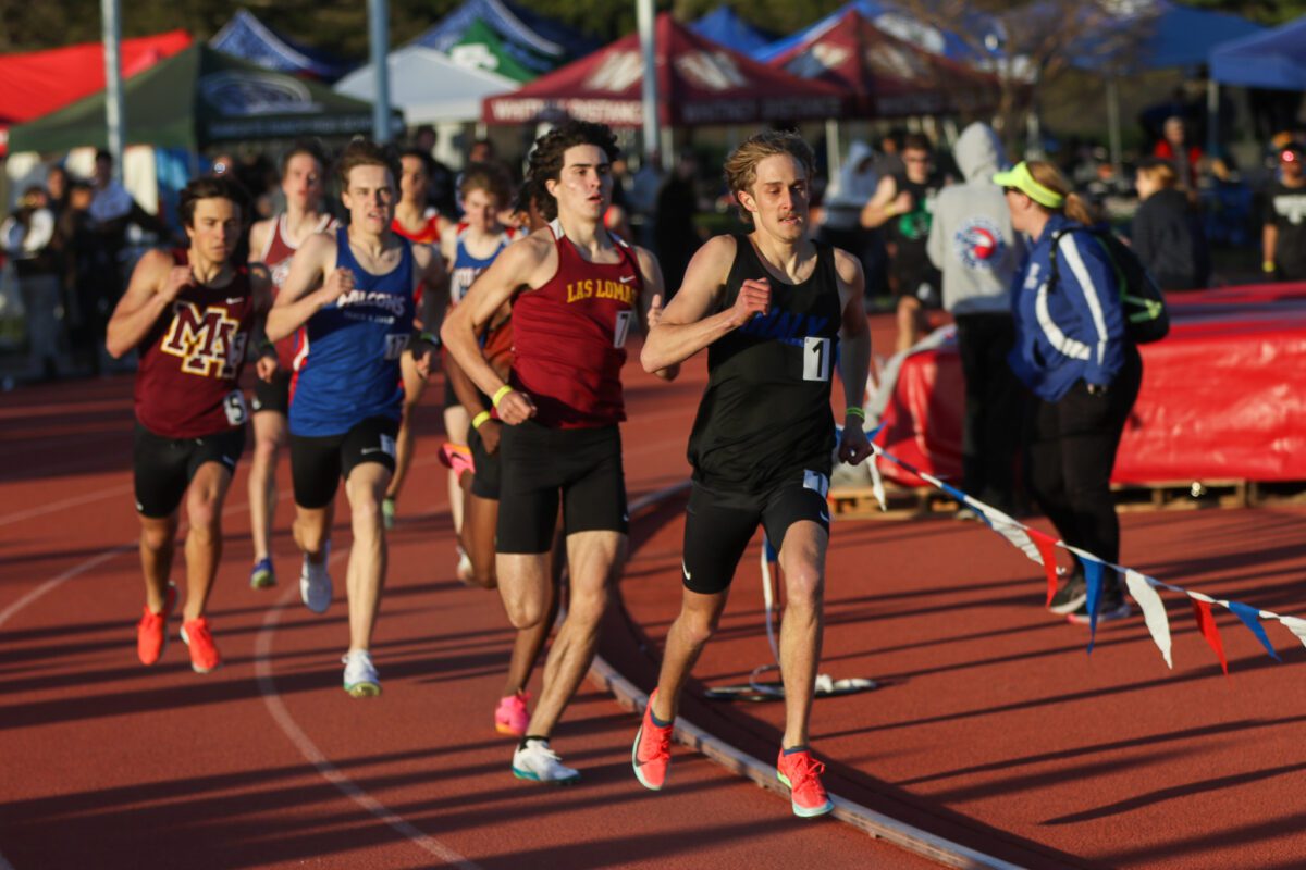 Lead man sprinting beside pennant-marked lane