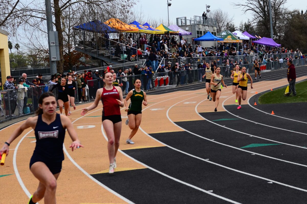 Young athletes exchanging baton on oval track