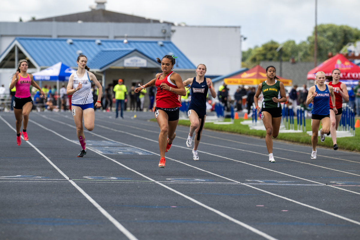 Female athlete in red airborne toward finish