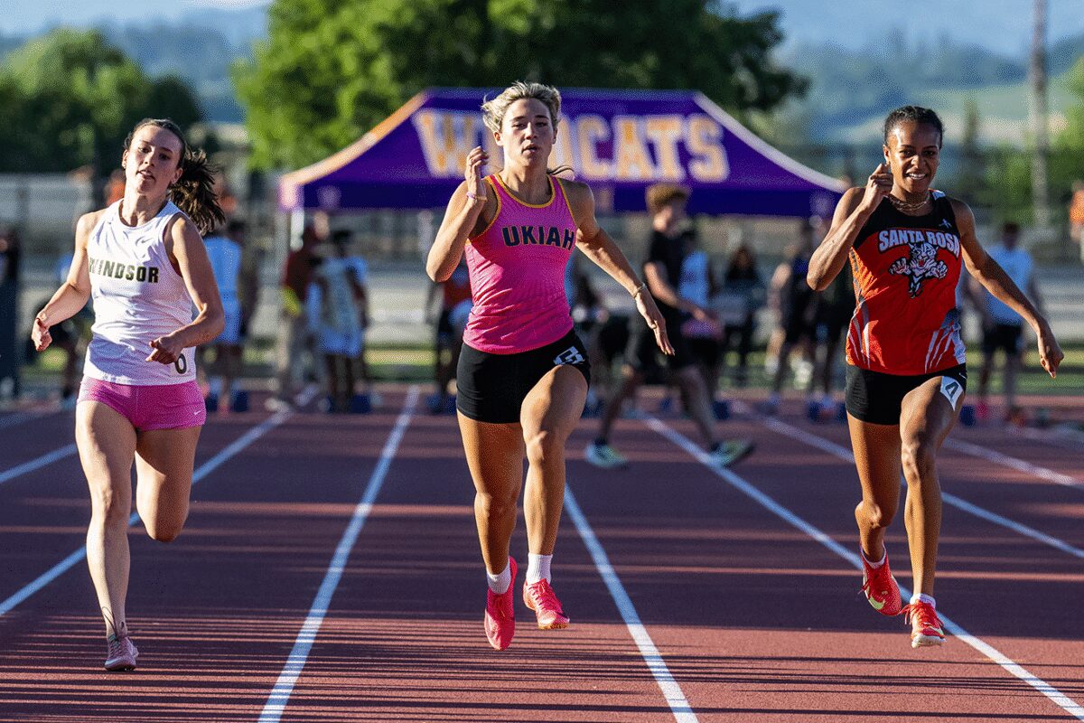 Sprinters racing past purple Wildcats tent