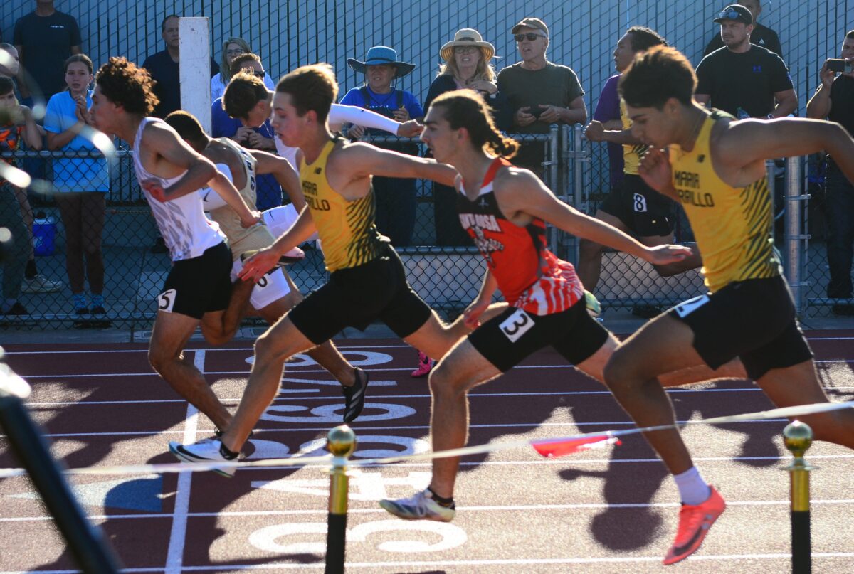 Four sprinters lunging together toward finish