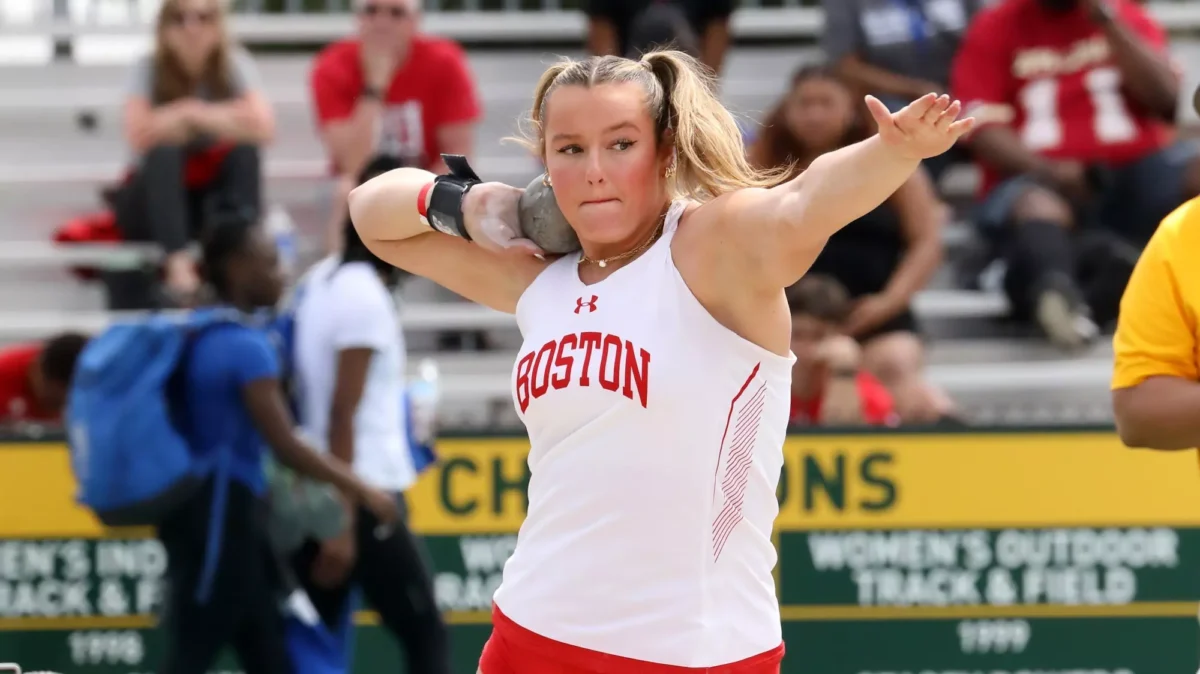 Female athlete in Boston singlet throws shot
