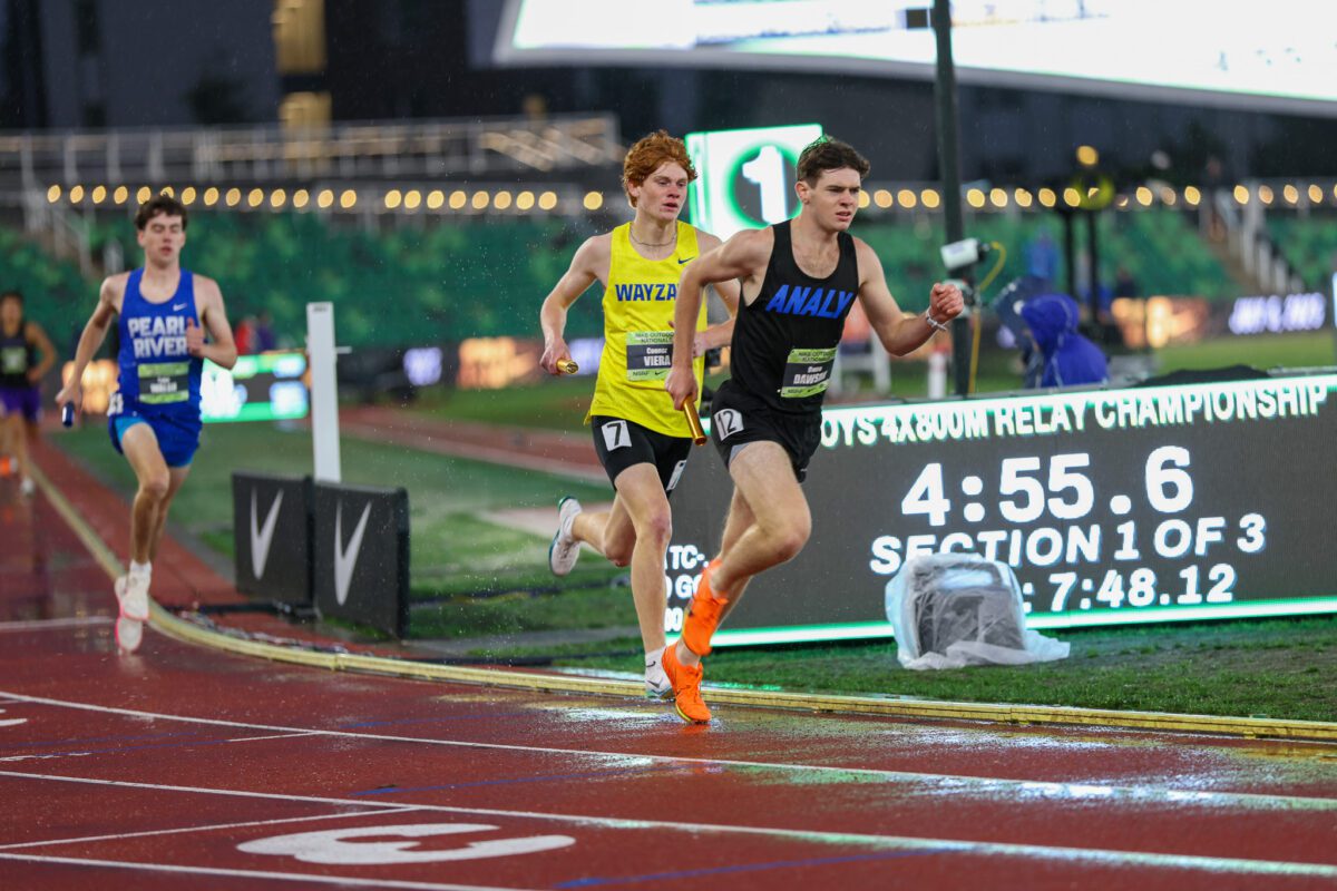 High school relay runners sprinting on wet track