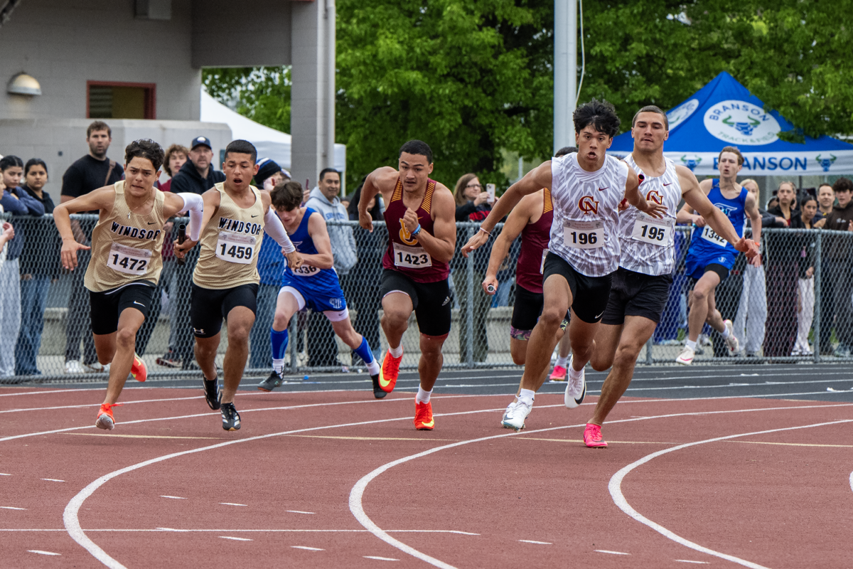 Male sprinters bursting forward on red track