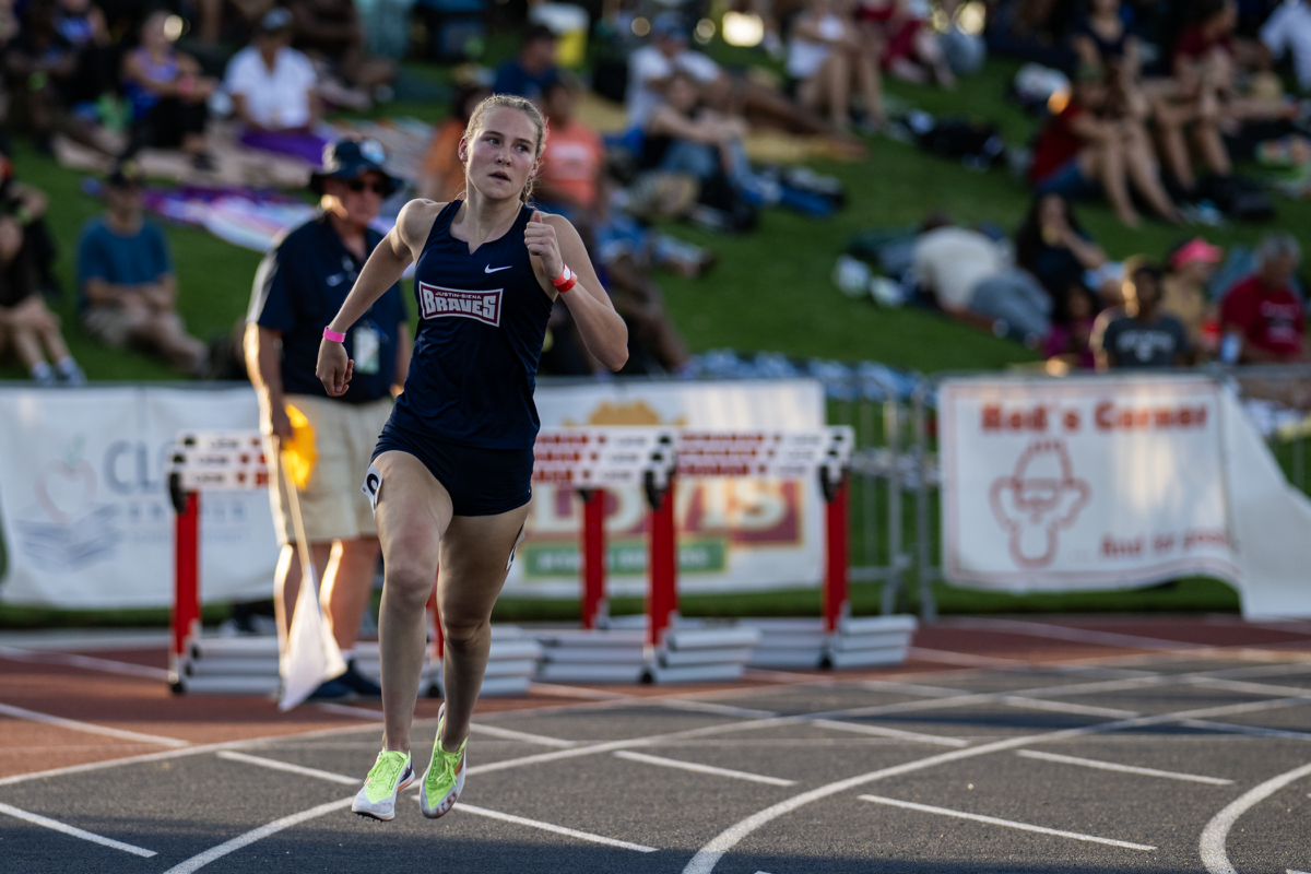Sprinter airborne above lanes at twilight meet