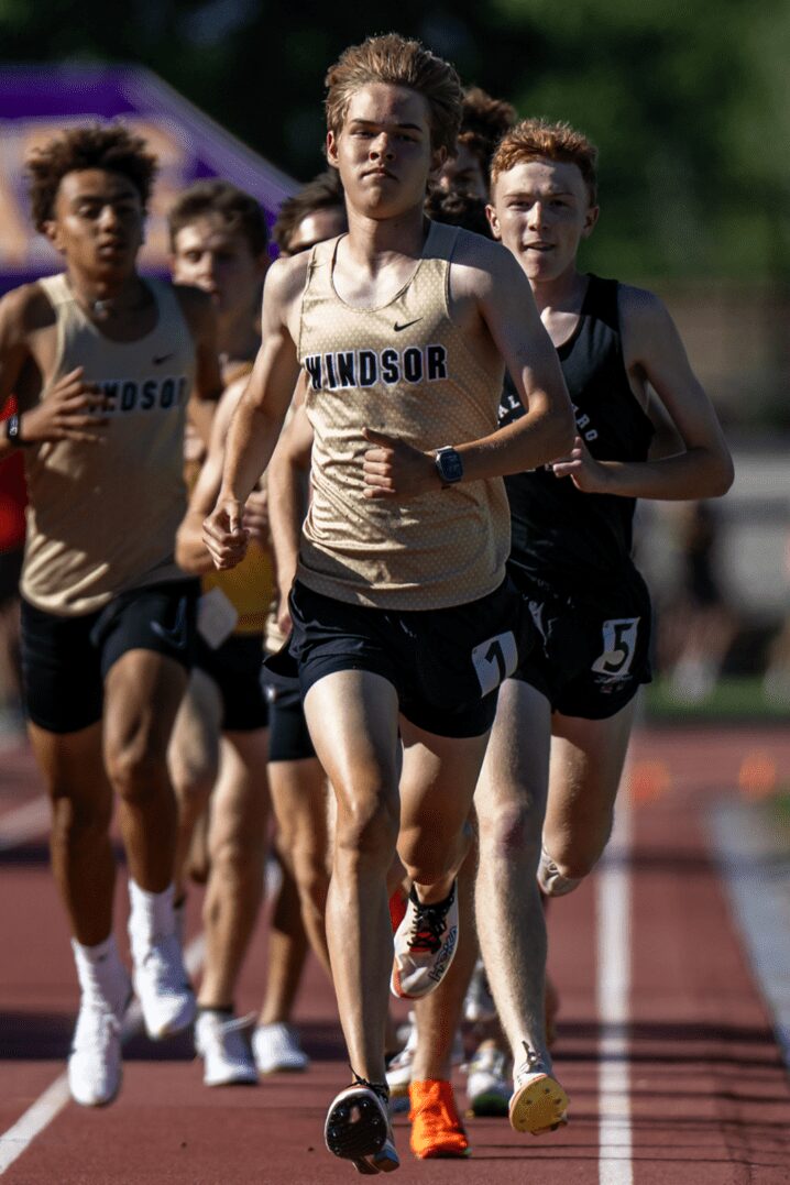 Runner with sports watch powering around track