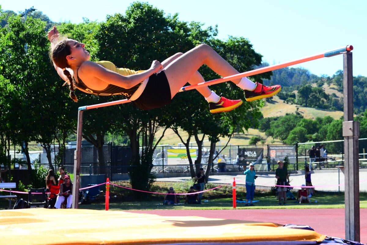 Female athlete clearing high jump bar outdoors
