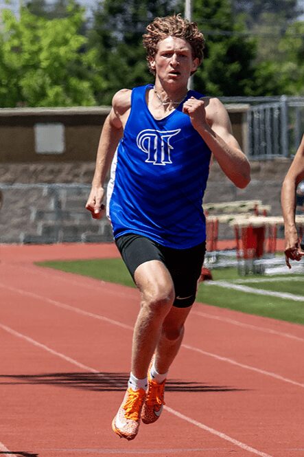 Runner in blue jersey sprinting on track