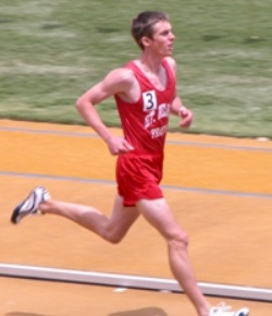 Male athlete sprinting on a track in a red uniform.