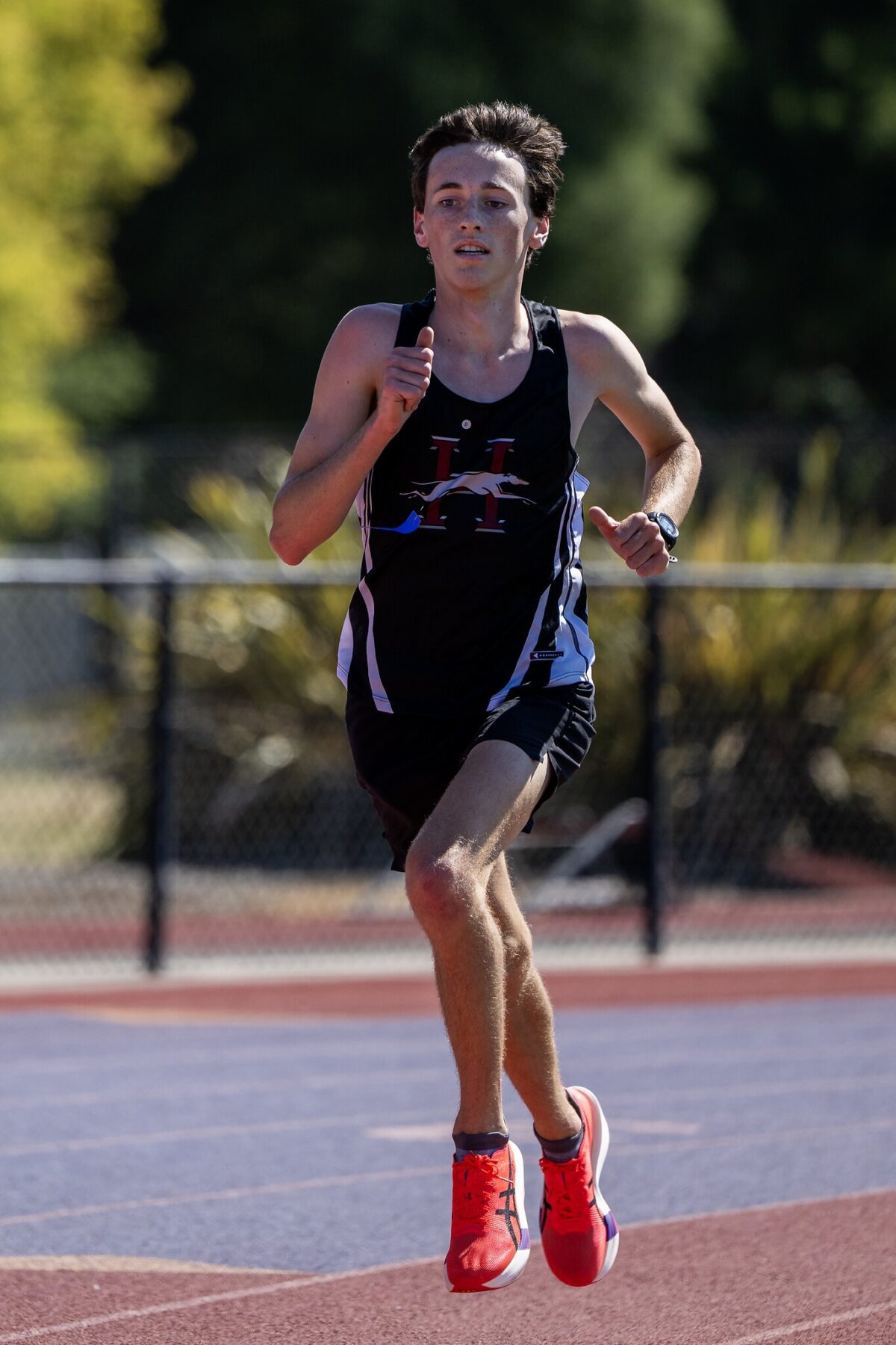 Young male runner competing on an outdoor track in athletic gear.