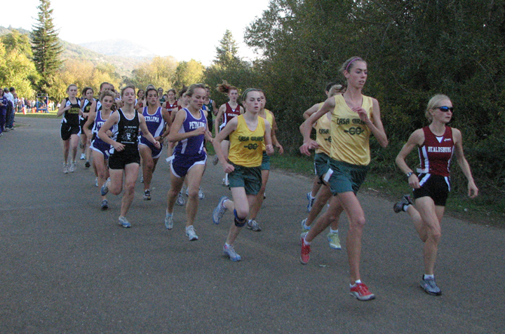 Runners competing in an outdoor cross-country race on a paved path.