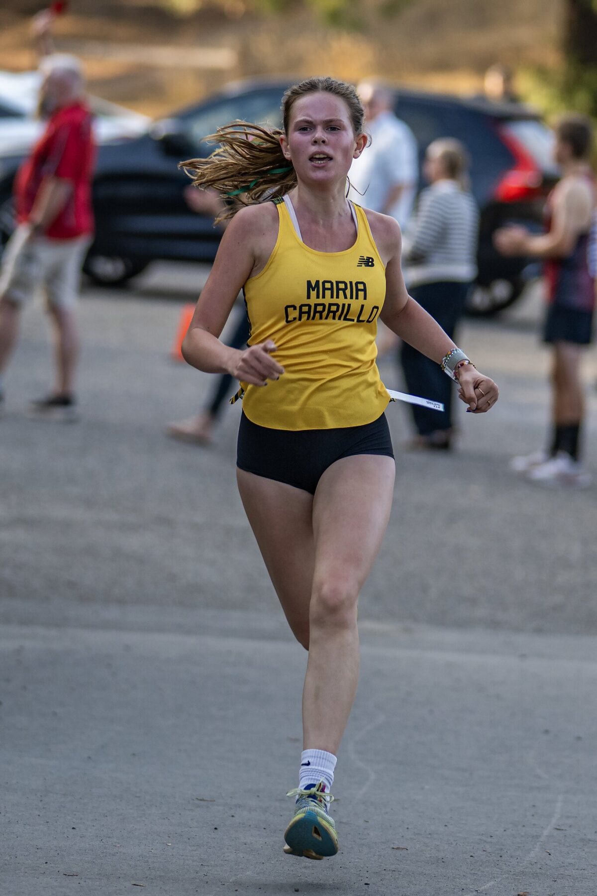 A female runner in a yellow tank top and black shorts during a race.
