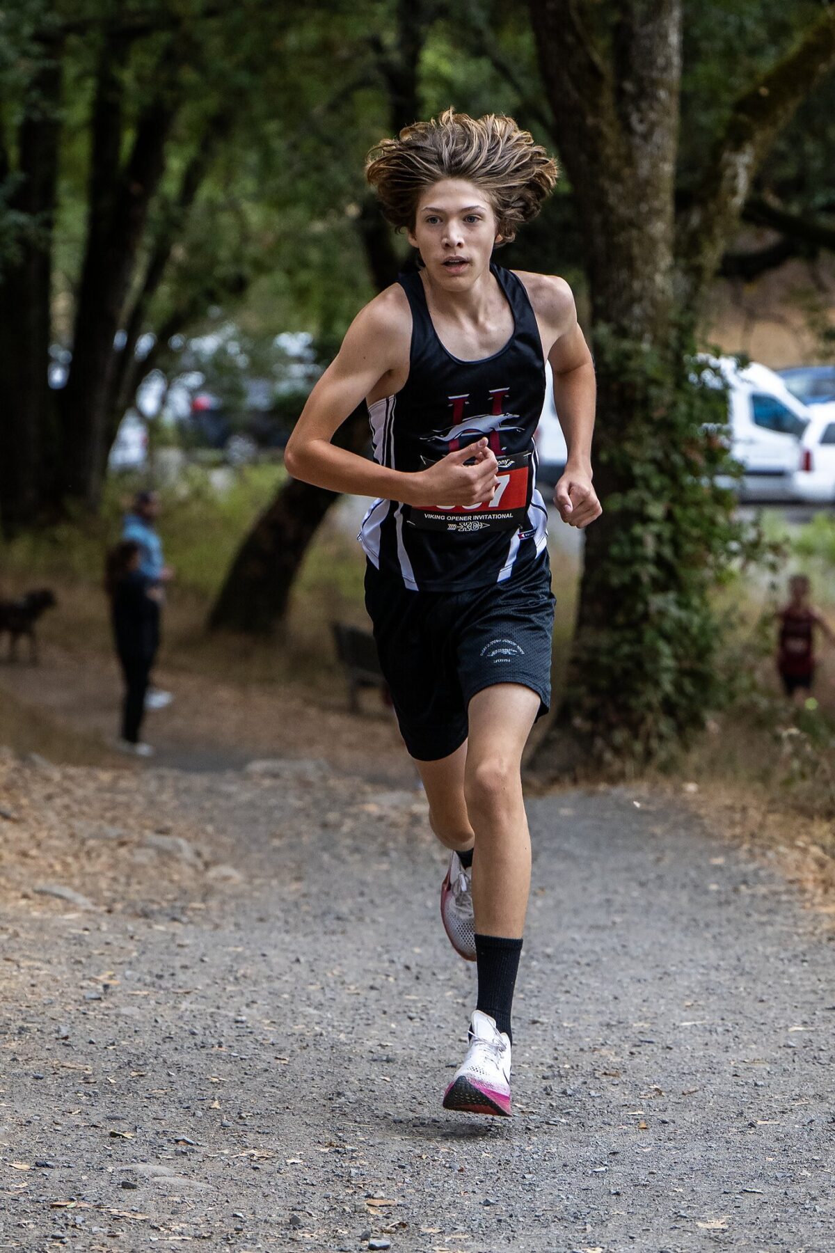 Young athlete running on a gravel trail during a race.