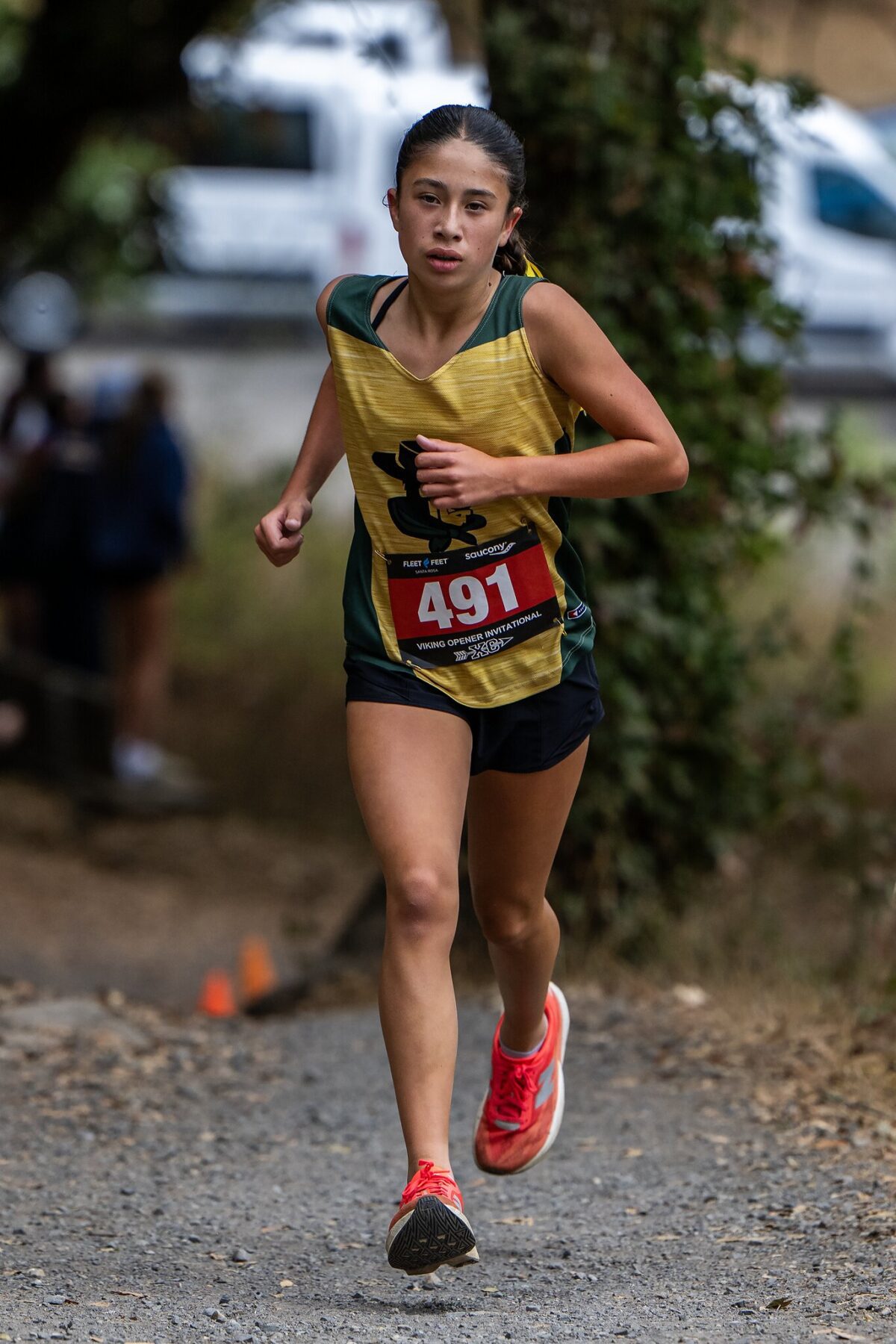 Young athlete running in a trail race wearing a yellow top and red shoes.